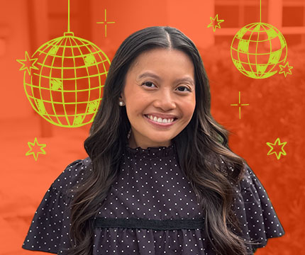 Jade_Hove | Website Design & Creative Marketing Agency | Baton Rouge | STUN Design Smiling woman with long dark hair in a black polka-dot blouse, orange backdrop with yellow party decorations (balls and stars).